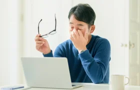 パソコン作業で目元を押さえる男性